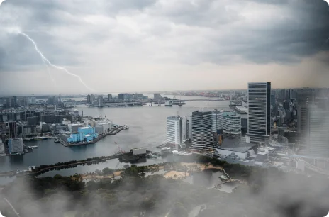 Stormy city skyline with lightning in the distance over high-rise buildings.